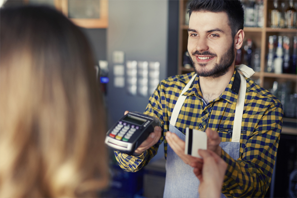 Retail customer service assistant taking payment at counter